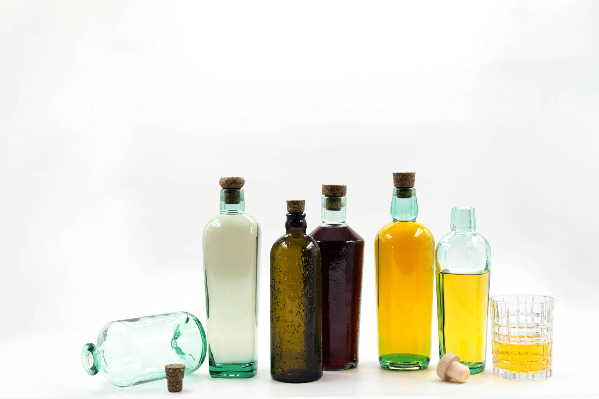 Verschieden gefüllte, dekorative Flaschen vor einem hellen Hintergrund