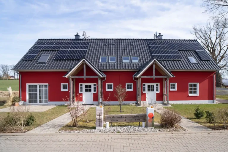 Ein rote Ferienhaus von der Eingangsseite mit Vorgarten.