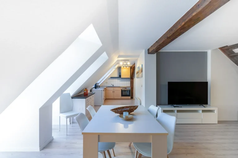 Panoramablich in einen großen Raum in einer Dachgeschosswohnung. Essbereich und Küche