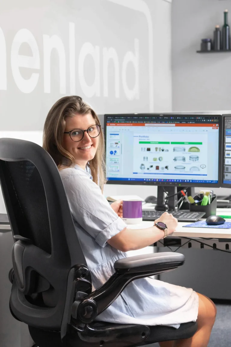 Eine junge Frau sitzt vor ihrem Monitor an ihrem Arbeitsplatz