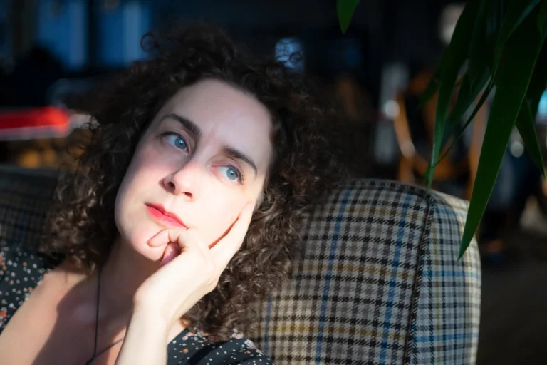 Eine Frau blickt nachdenklich in die Kamera. Licht fällt von der Seite auf ihr Gesicht.