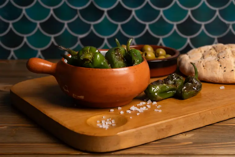 Bratpaprika und Oliven angerichtet auf einem Holzbrett