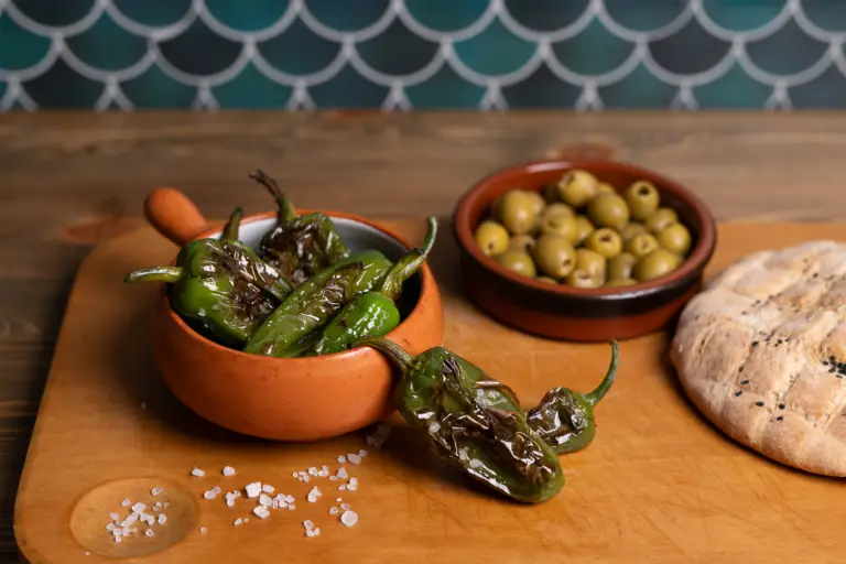 Oliven und Bratpaprika angerichtet auf einem Holzbrett