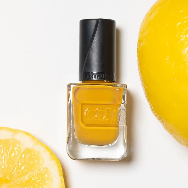 Eine Flasche mit gelben Nagellack und Zitronen im Hintergrund